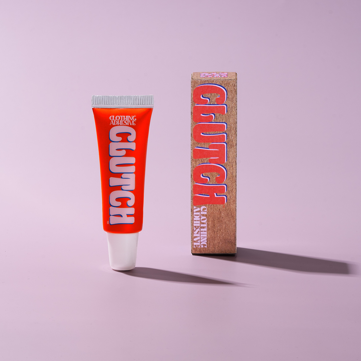 Red tube of clutch glue clothing adhesive that holds your clothes in place. 100% recyclable and recycled tube alternative to fashion tape and hollywood tape for women